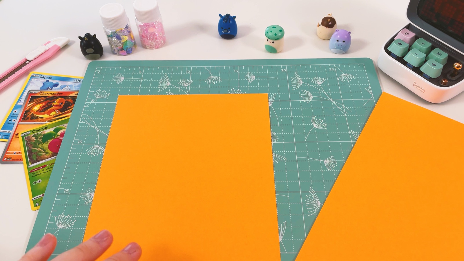 Zwei lange Hälften aus orangem Papier auf der Schneidematte, nachdem ein Blatt halbiert wurde