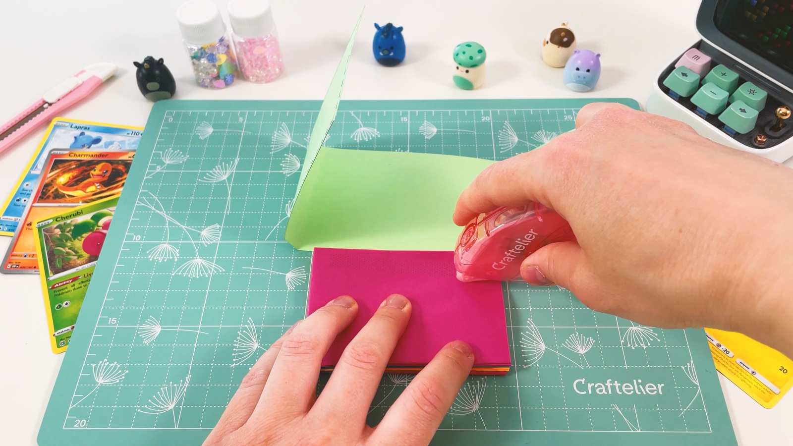 Das äußere rosa Fach des Stapels wird eingeklebt, bevor es in die grüne Hülle gedrückt wird