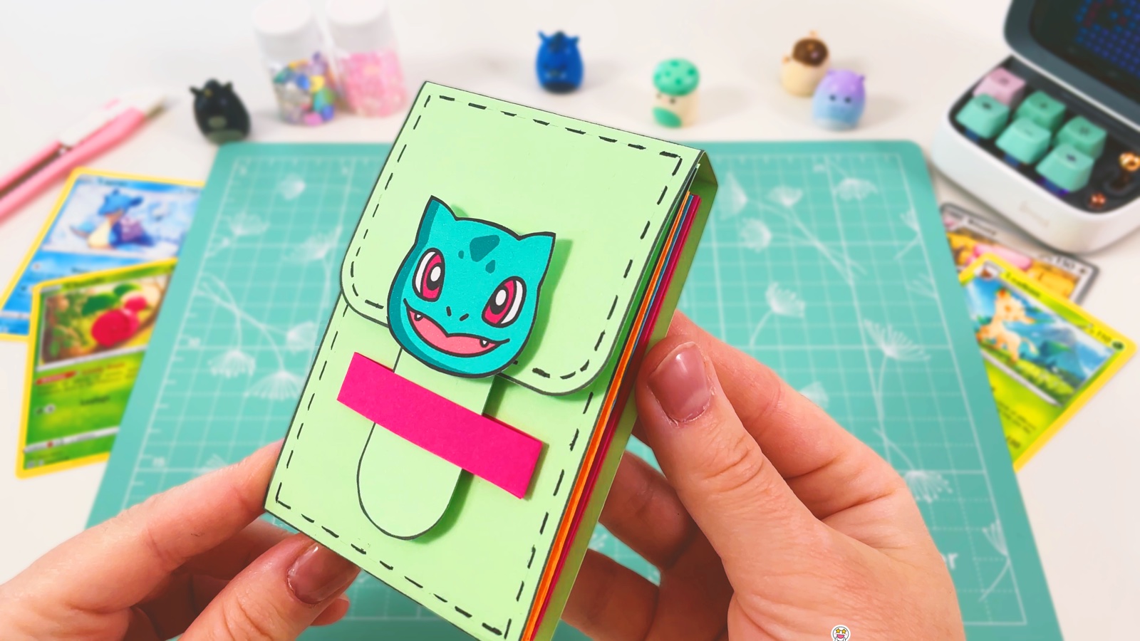 Finished green paper card holder with a Bulbasaur face on the flap and a pink band