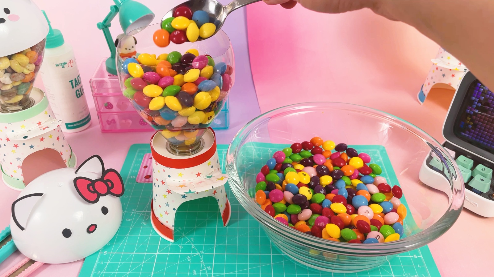 Des bonbons colorés versés à la cuillère dans le réservoir, depuis un bol en verre