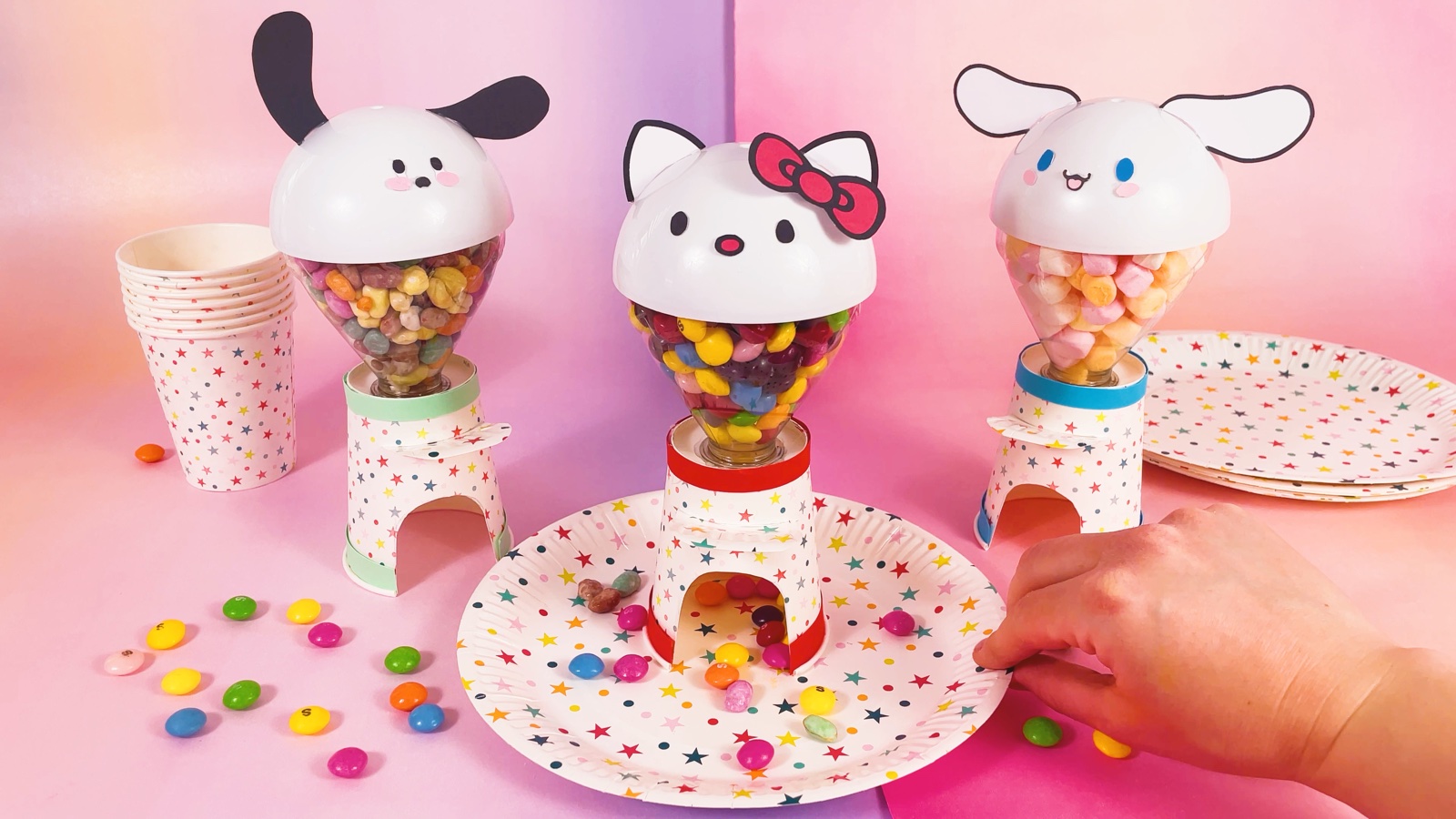 Trois distributeurs terminés, Pochacco, Hello Kitty et Cinnamoroll, remplis de bonbons, avec des friandises sur une assiette à étoiles