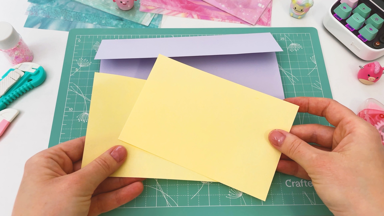 Dos mitades de papel amarillo sostenidas frente a la billetera lila doblada