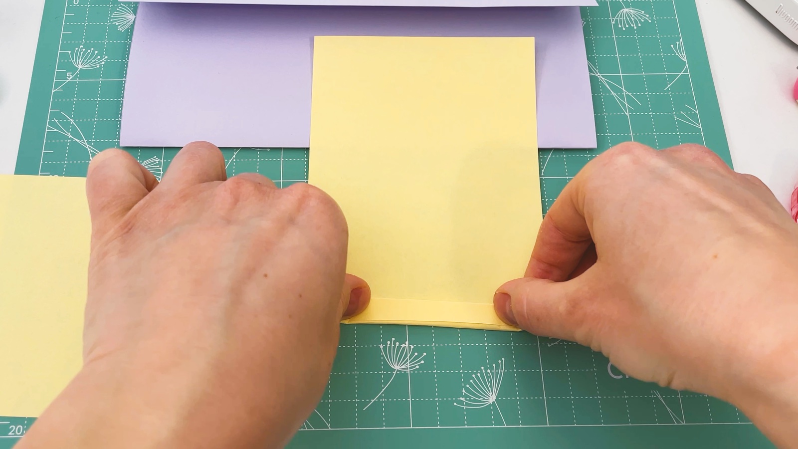 Se dobla una tira angosta por el borde de abajo del papel amarillo para empezar el zigzag