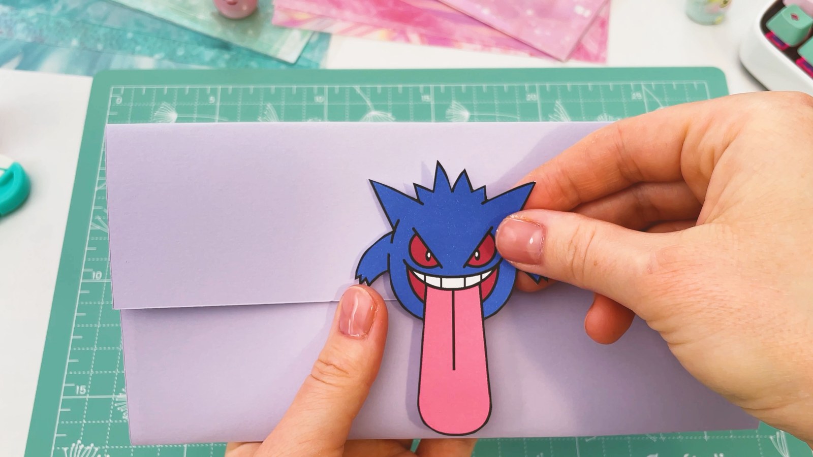 Se presiona a Gengar sobre la solapa lila, con su larga lengua rosa colgando sobre el frente