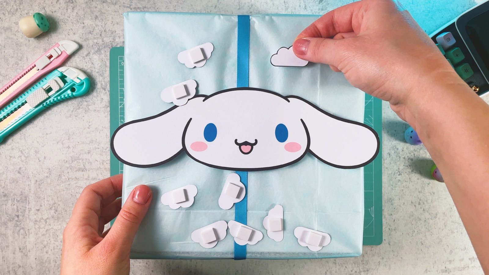 Se pegan nubecitas de papel blanco alrededor de la carita de Cinnamoroll