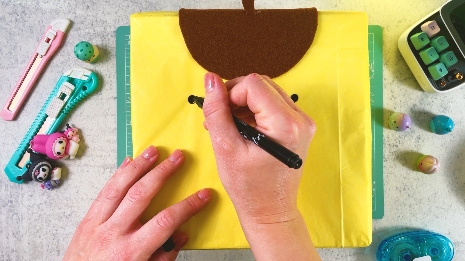 Se dibujan los ojos y la boca de Pompompurin sobre el papel amarillo con un marcador negro