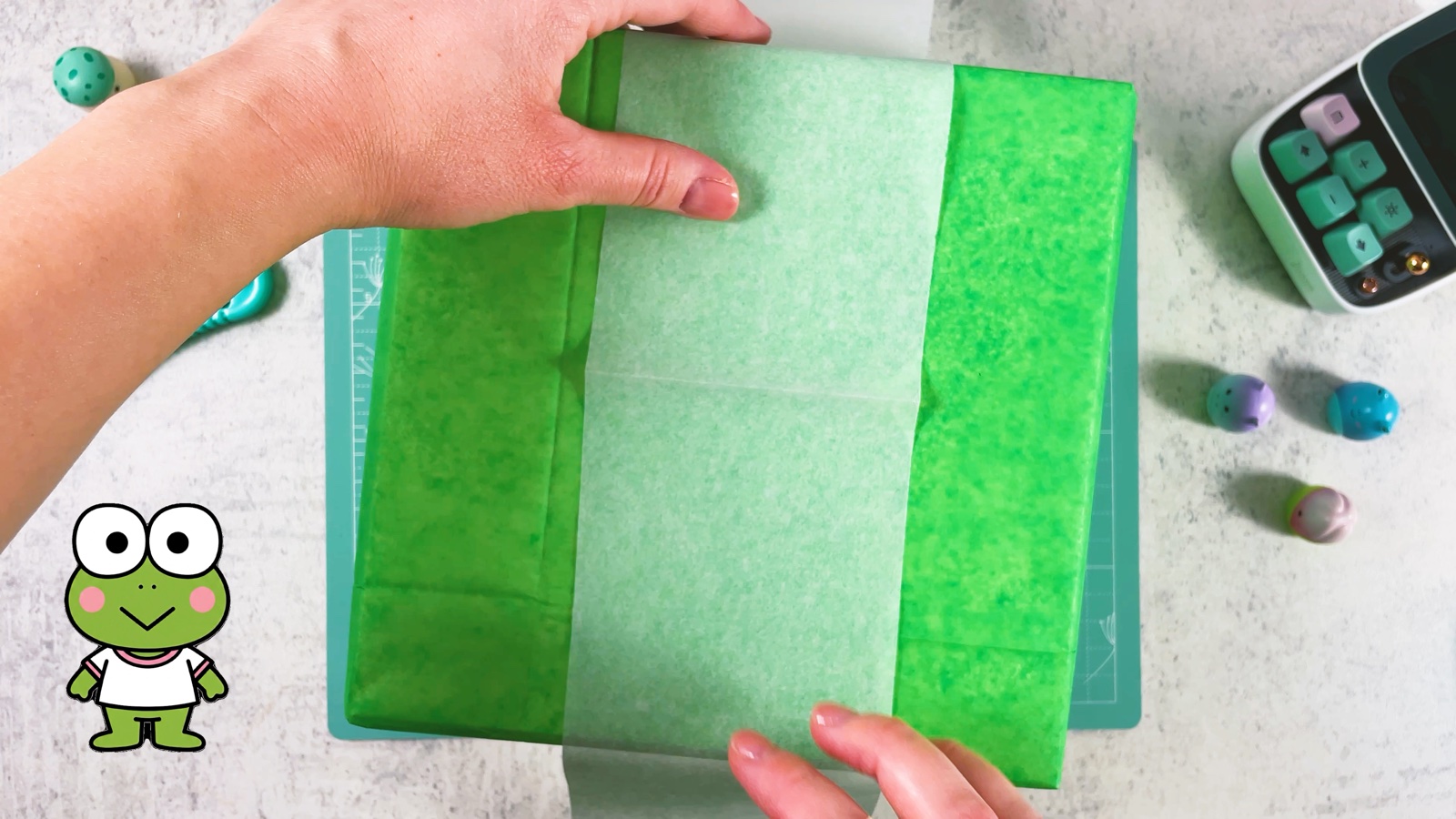 Se coloca una tira ancha de papel de regalo verde pálido por el centro de una caja verde