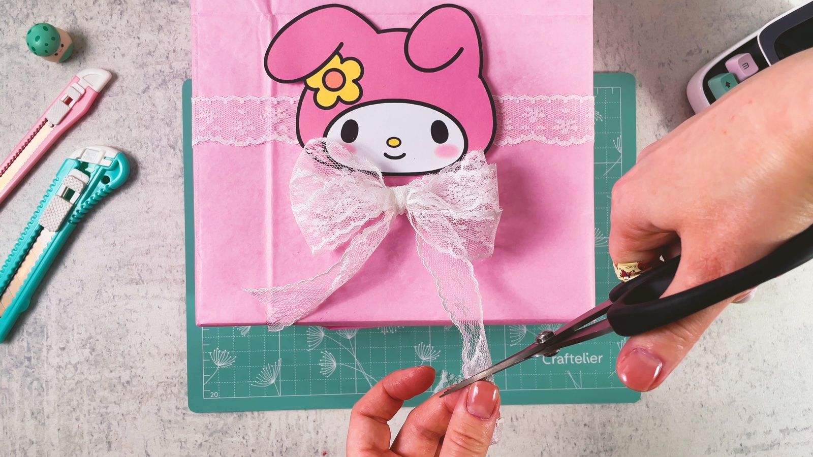 Se cortan con tijeras las puntas del moño de encaje bajo la carita de My Melody