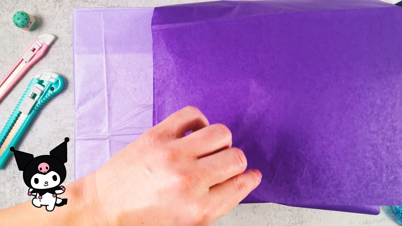 Se envuelve con papel de regalo morado oscuro la mitad de abajo de una caja lila