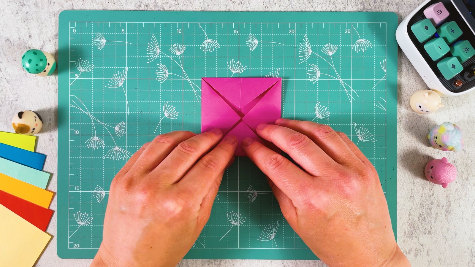 The pink paper as a small square with all four corners folded in to meet in the middle