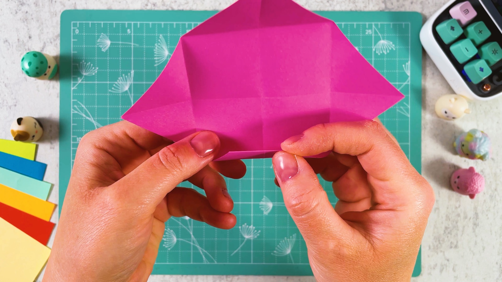 Folding the bottom corner of the pink square up into a narrow band along the fold line