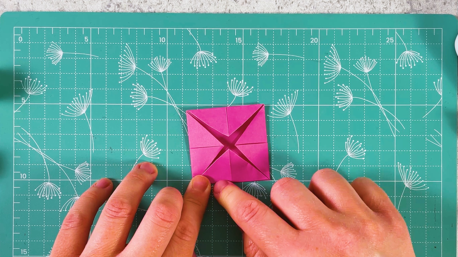 The small pink square seen from above with four corners folded in to the centre, making an X