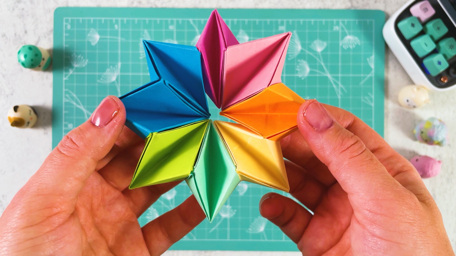 The finished origami infinity star opened flat, with eight pointed tips in blue, pink, orange, yellow, mint and green