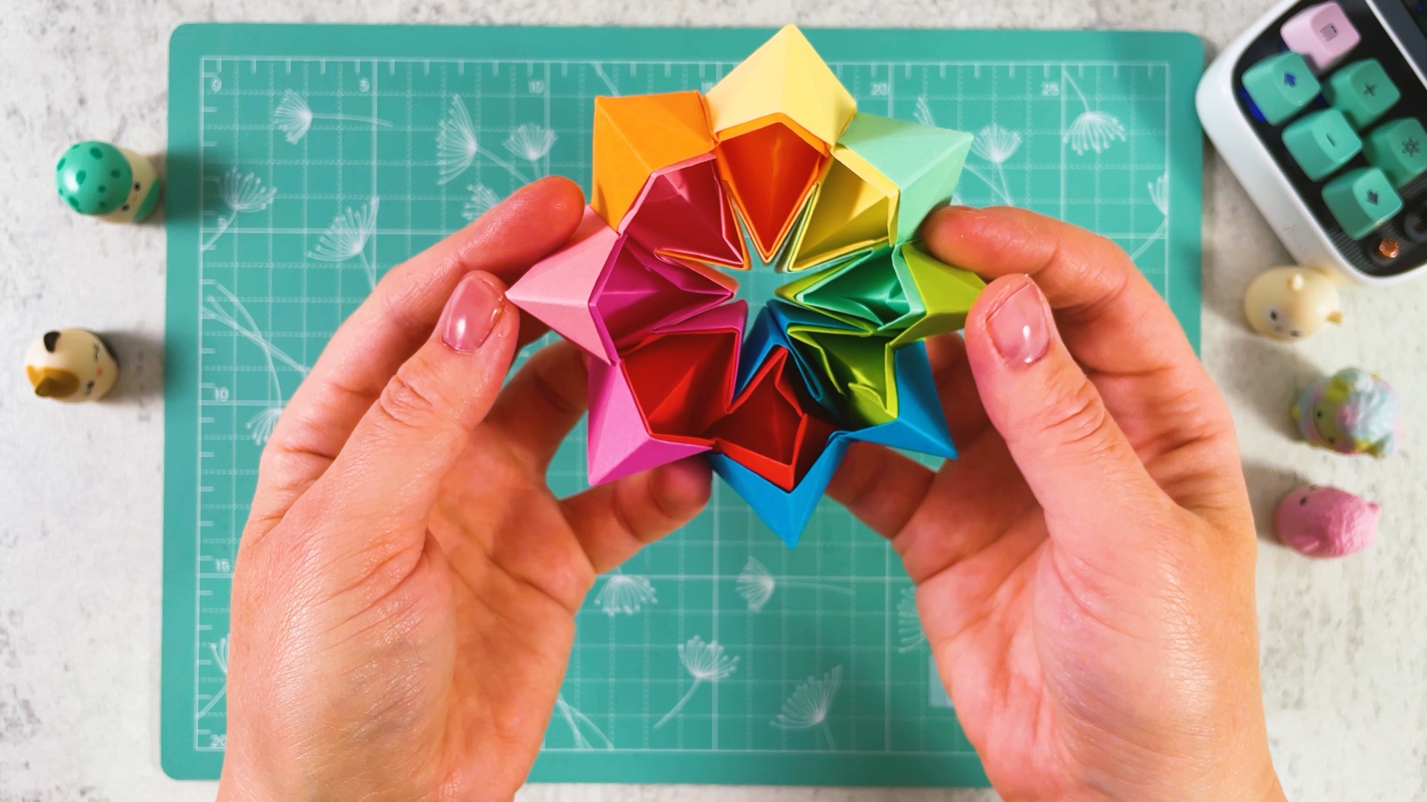 The rainbow paper toy folded into a round flower shape with a small star-shaped hole in the centre