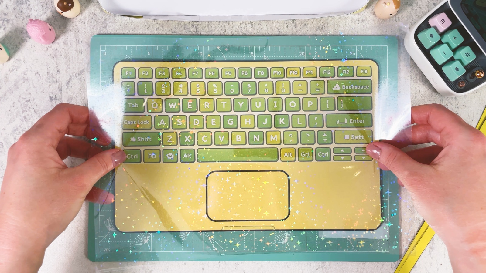 Klare Folie wird über der grün-gelben Tastatur glatt gestrichen
