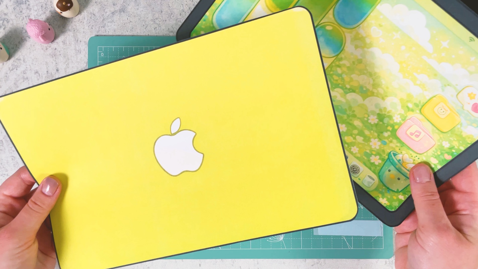 Der ausgeschnittene gelbe Deckel mit einem weißen Apple-Logo neben dem Bildschirm