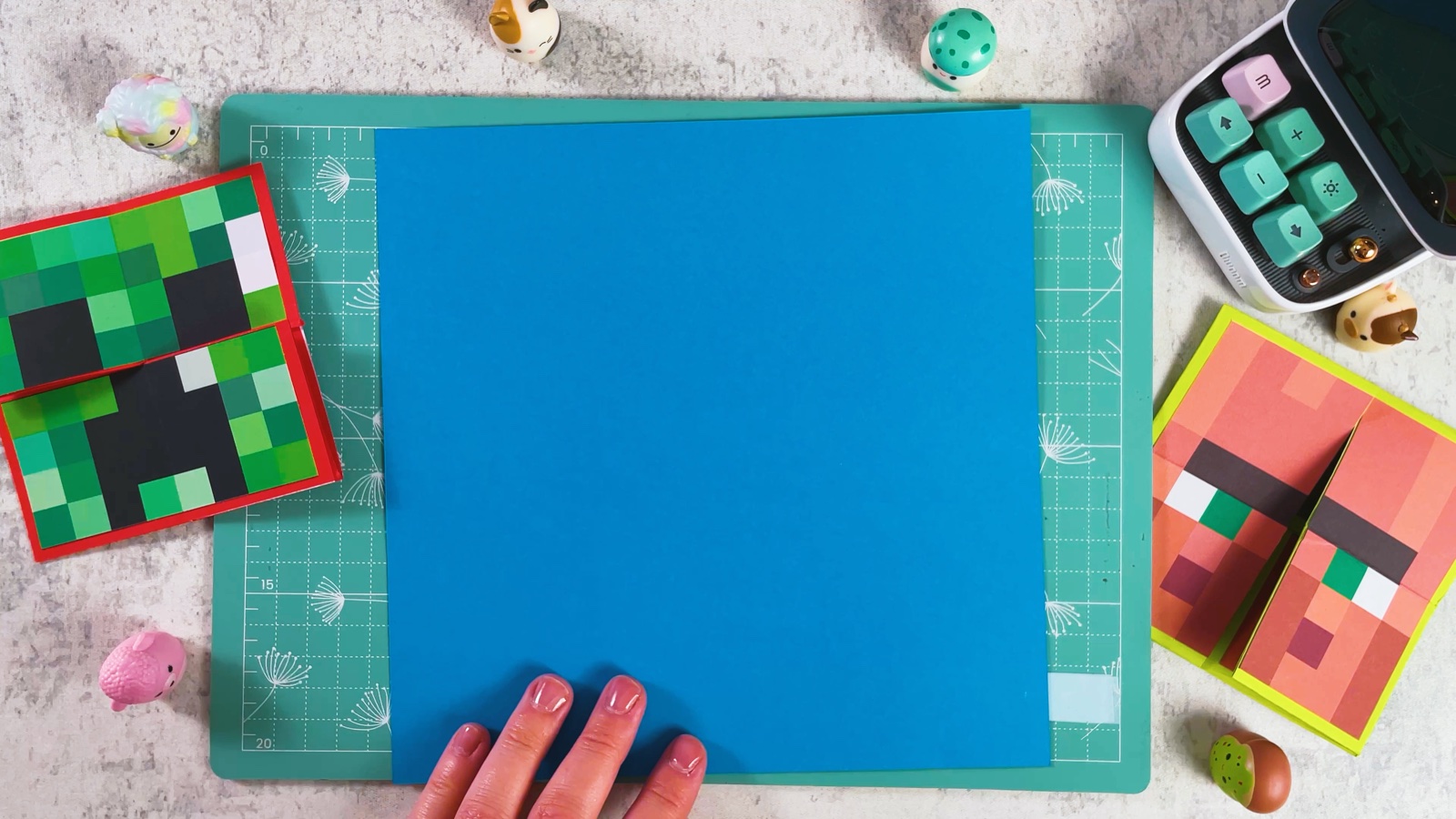 A square of blue paper on a green cutting mat