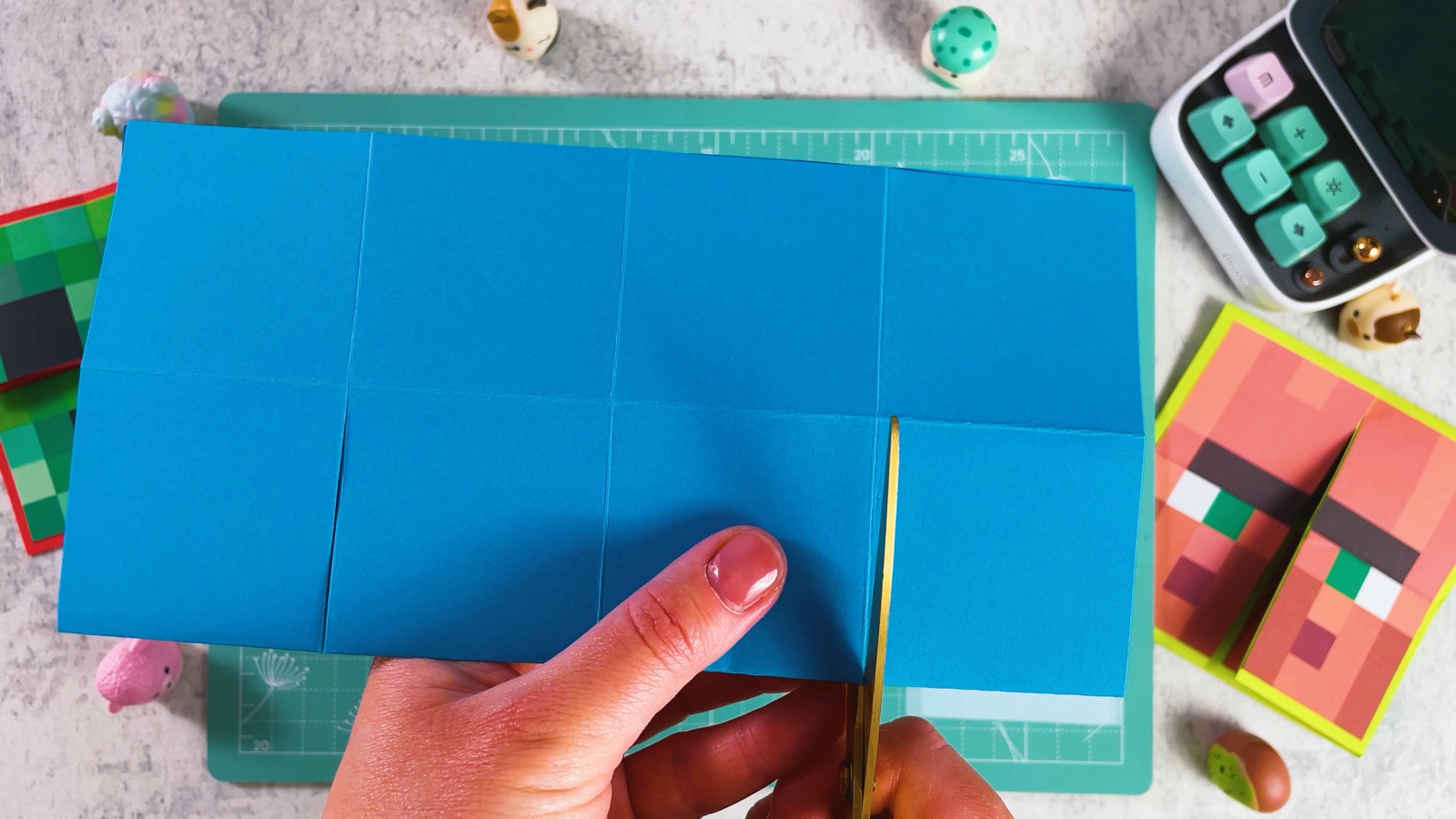 Cutting into the folded blue paper along a crease, one square deep