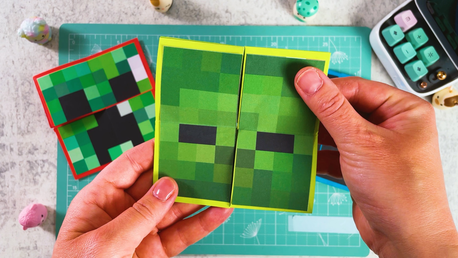 A finished Minecraft paper flip toy with a yellow frame, showing the green Zombie face