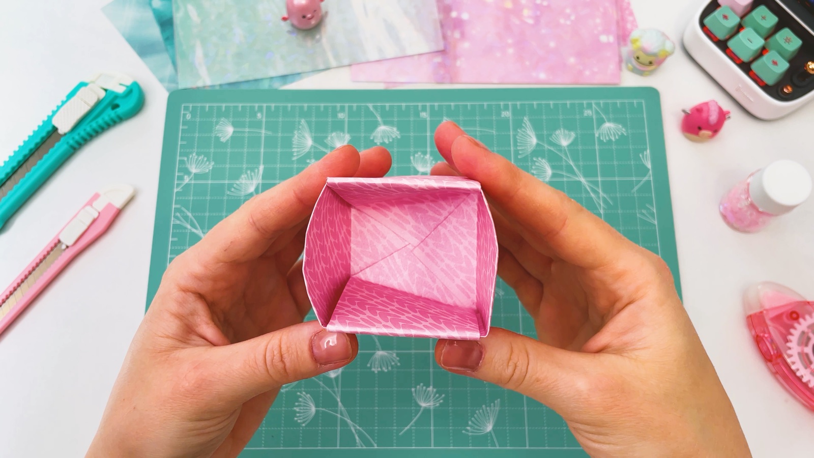 Blick von oben in die fertige rosa Papierschachtel, die gefalteten Laschen liegen flach am Boden