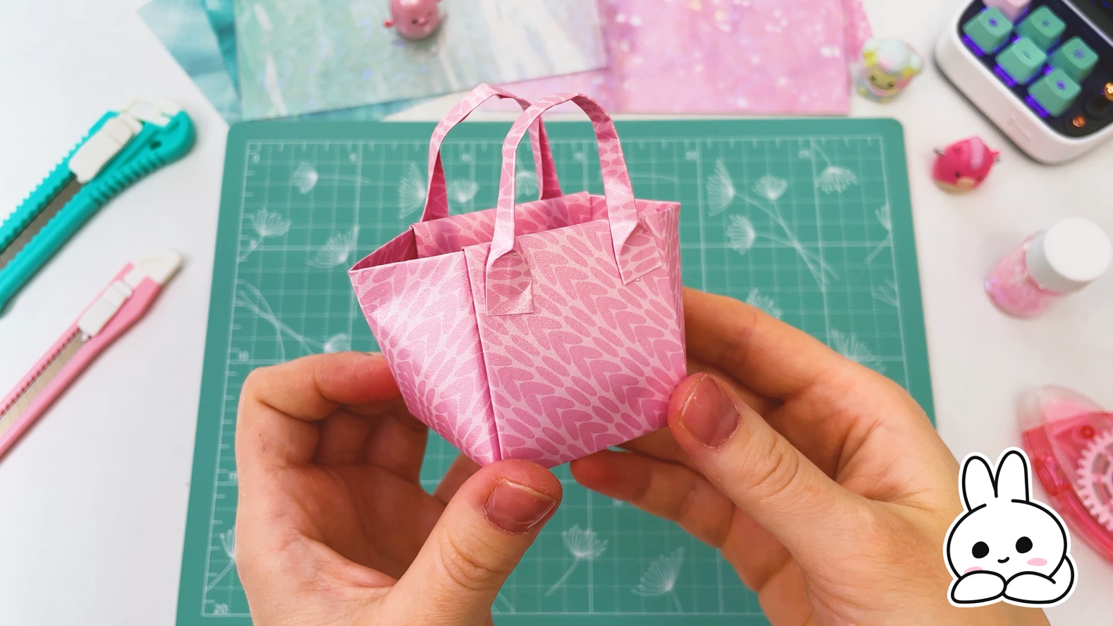 Die rosa Papiertasche mit zwei Henkeln, in zwei Händen gehalten