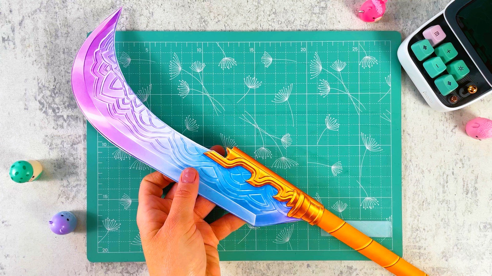 Finished paper Mira Gokdo with a curved pink and blue blade on a gold pole
