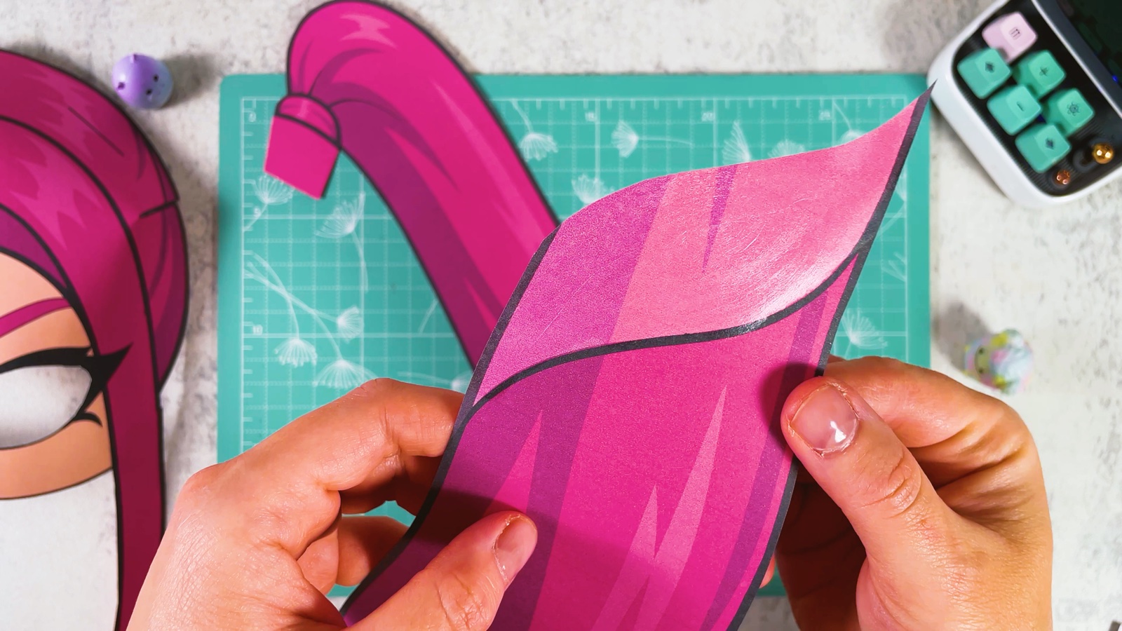 Laying the ponytail piece with the hair tie over the glued light pink part of the second piece