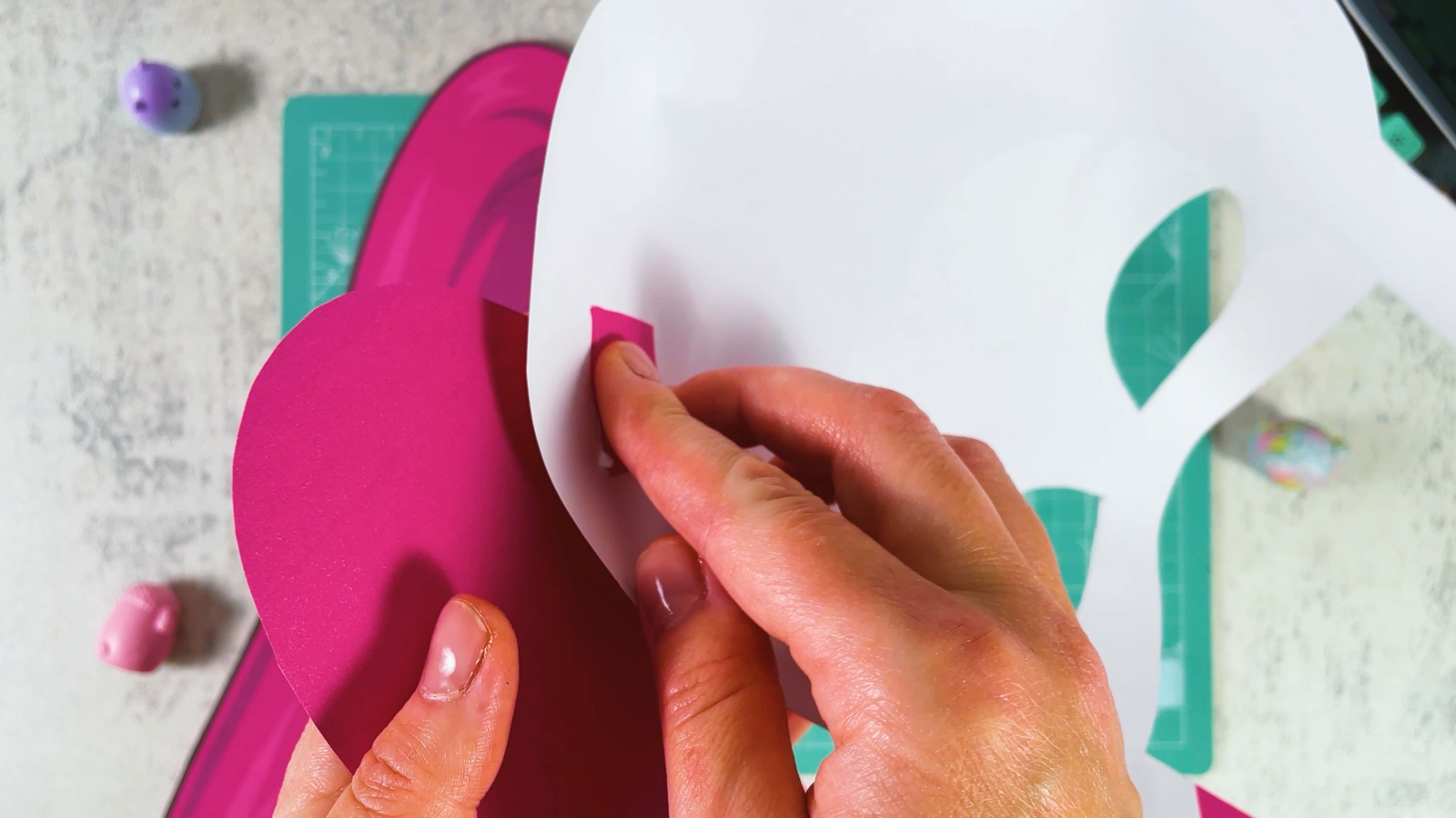 The back of the mask, pressing the pink tab flat onto the white paper