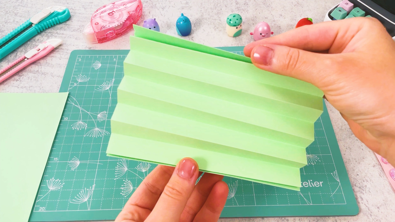 Le papier vert plié en accordéon, un peu écarté pour montrer les plis