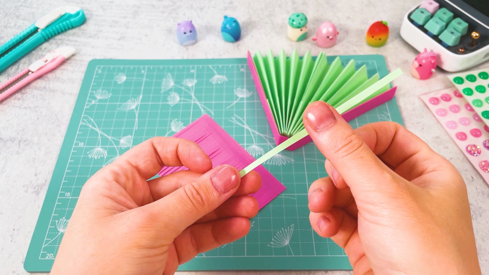 Une fine bande de papier vert tenue à côté des franges roses