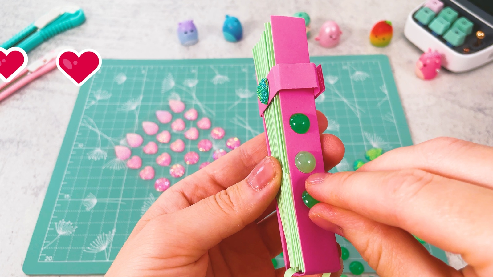 Des strass ronds verts collés le long de la baguette rose de l’éventail fermé