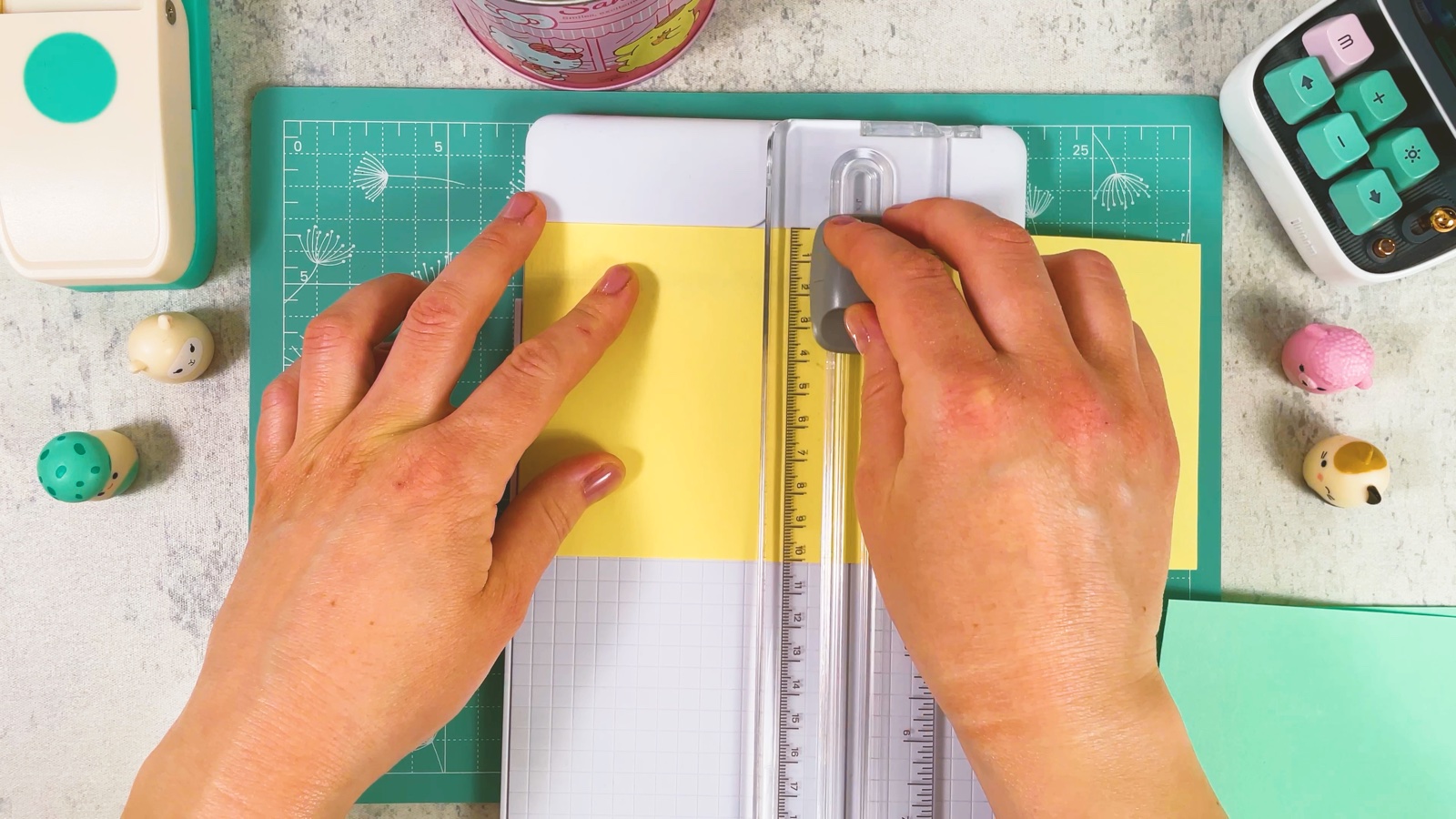 Ein Quadrat wird am Papierschneider aus gelbem Papier geschnitten, daneben liegt mintgrünes Papier bereit