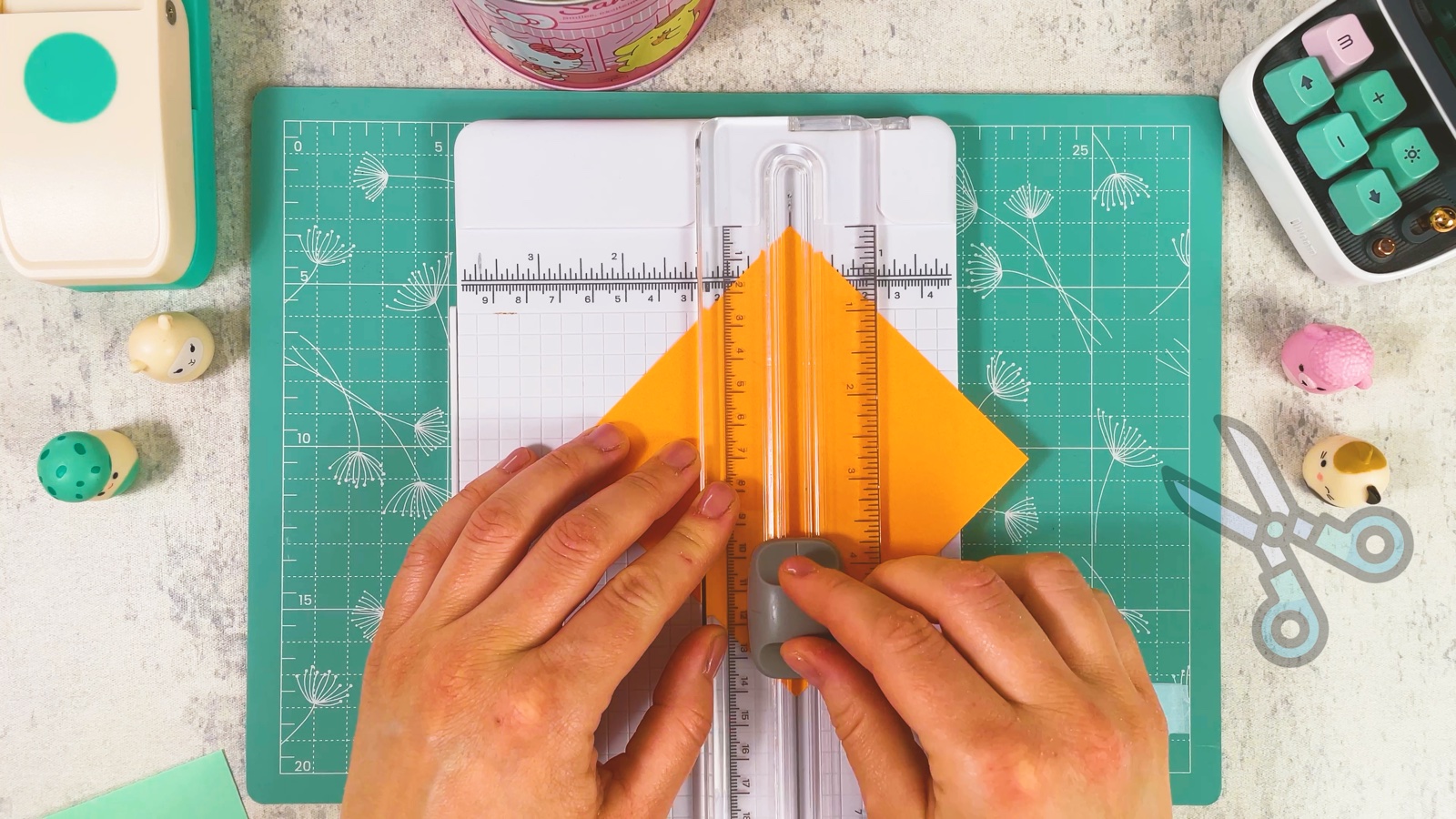Ein oranges Quadrat wird am Papierschneider diagonal halbiert