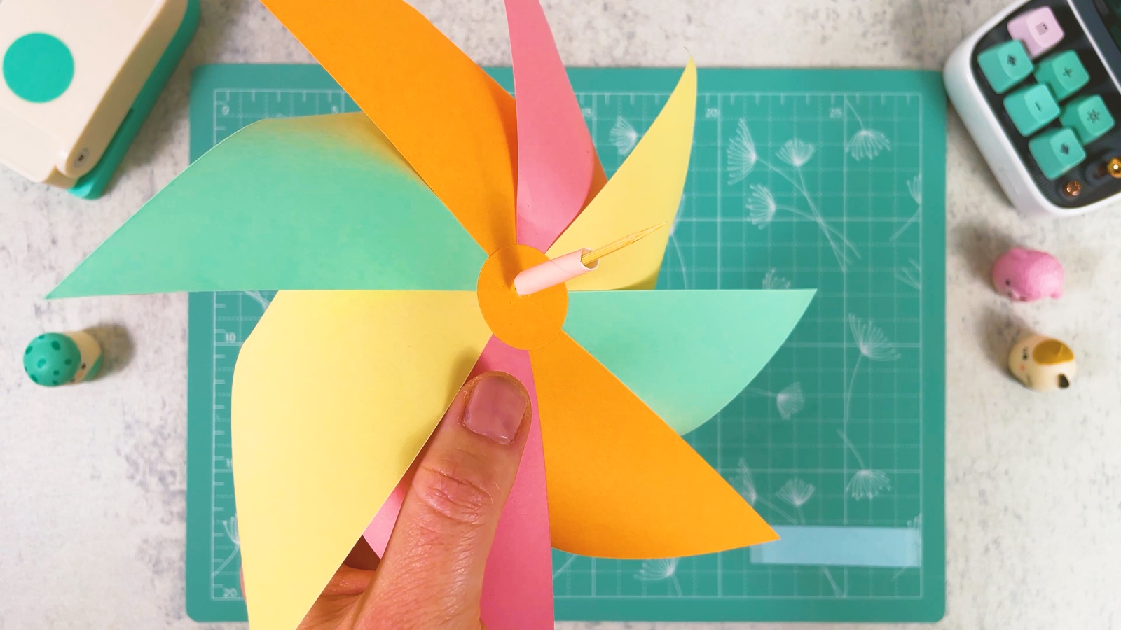 Nahaufnahme eines kurzen Stücks rosa Papierstrohhalm auf dem Zahnstocher, direkt hinter dem orangen Kreis auf der Rückseite des Windrads