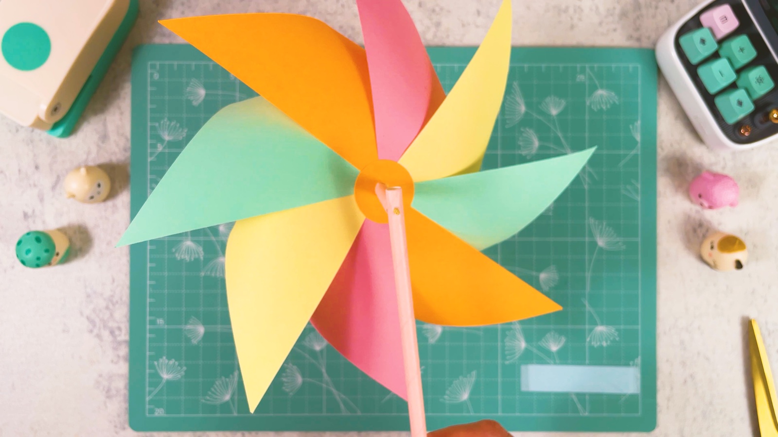 Die Rückseite des fertigen Windrads, der rosa Strohhalmgriff verläuft hinter der orangen Mitte nach unten