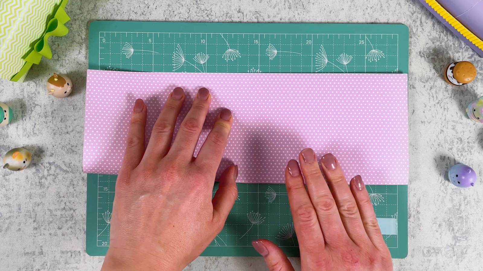 Pressing a crease along a pink polka dot sheet folded in half the long way