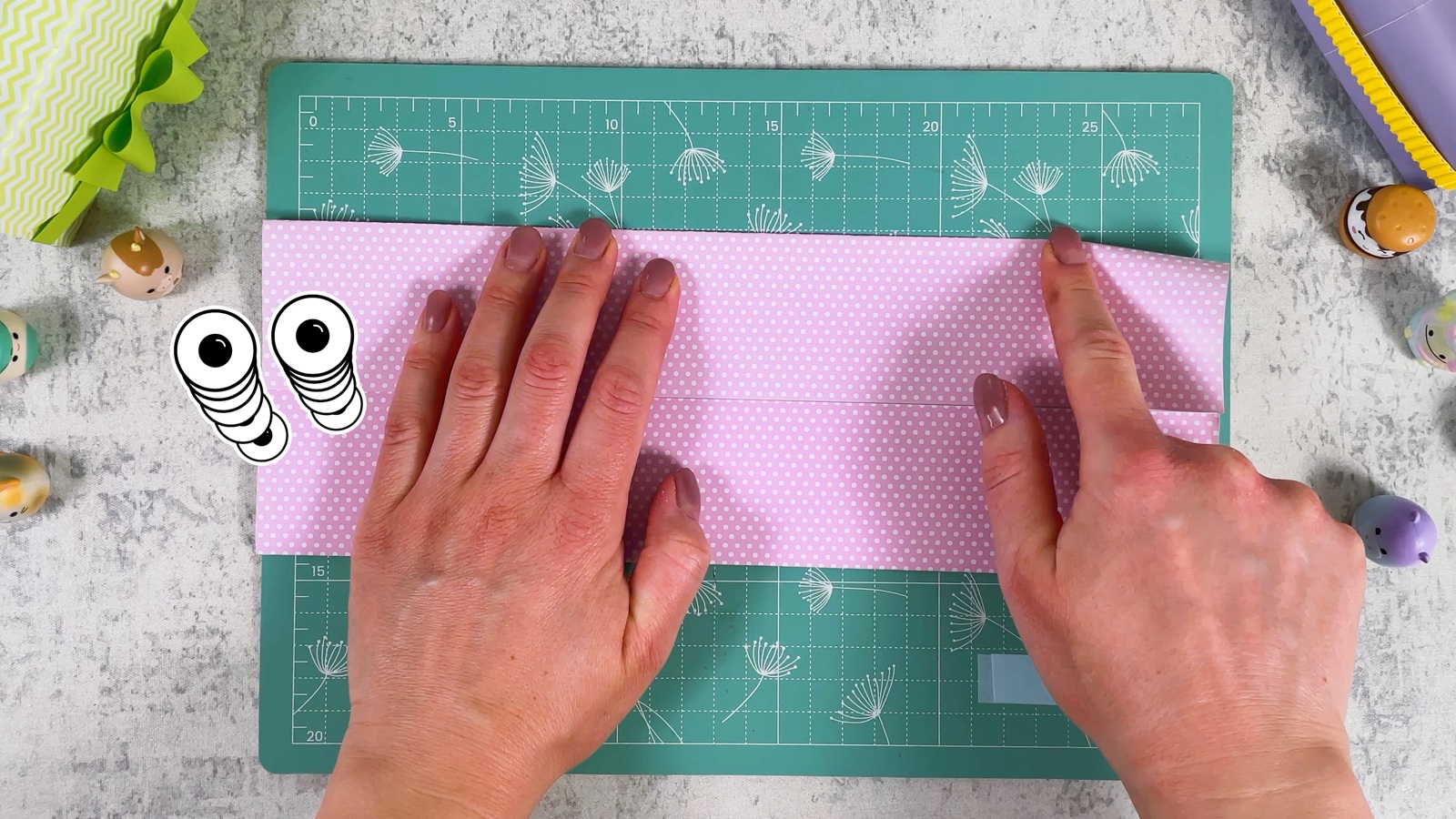 Both long edges of the sheet folded to the middle crease, making a long pink strip