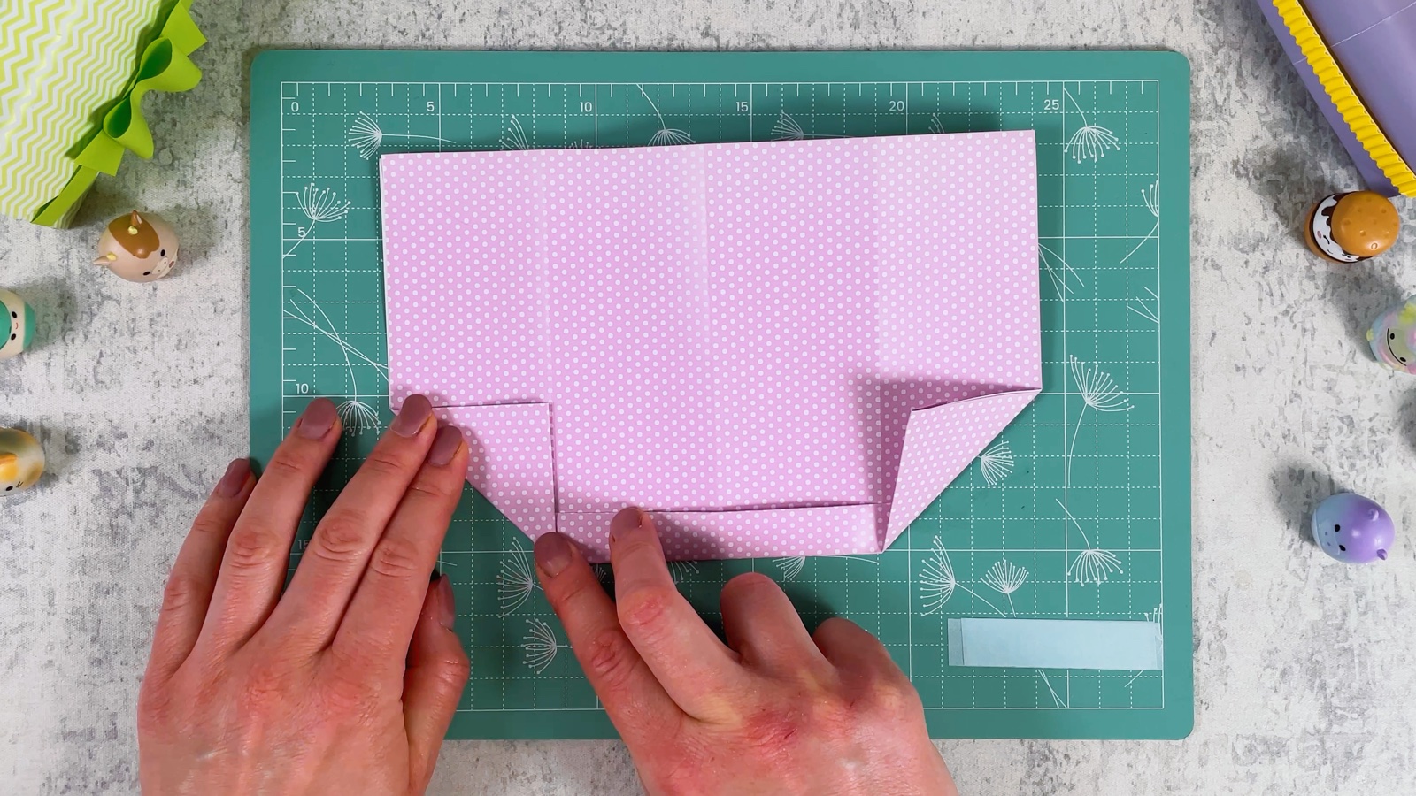 Both bottom corners of the pink paper folded up into small triangles