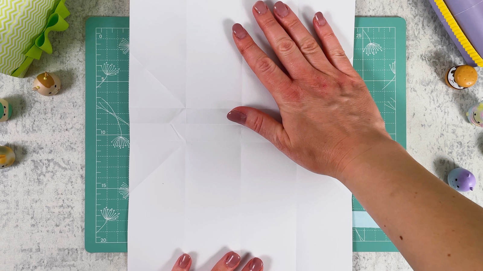 The opened white sheet with a grid of creases, smoothed flat by hand