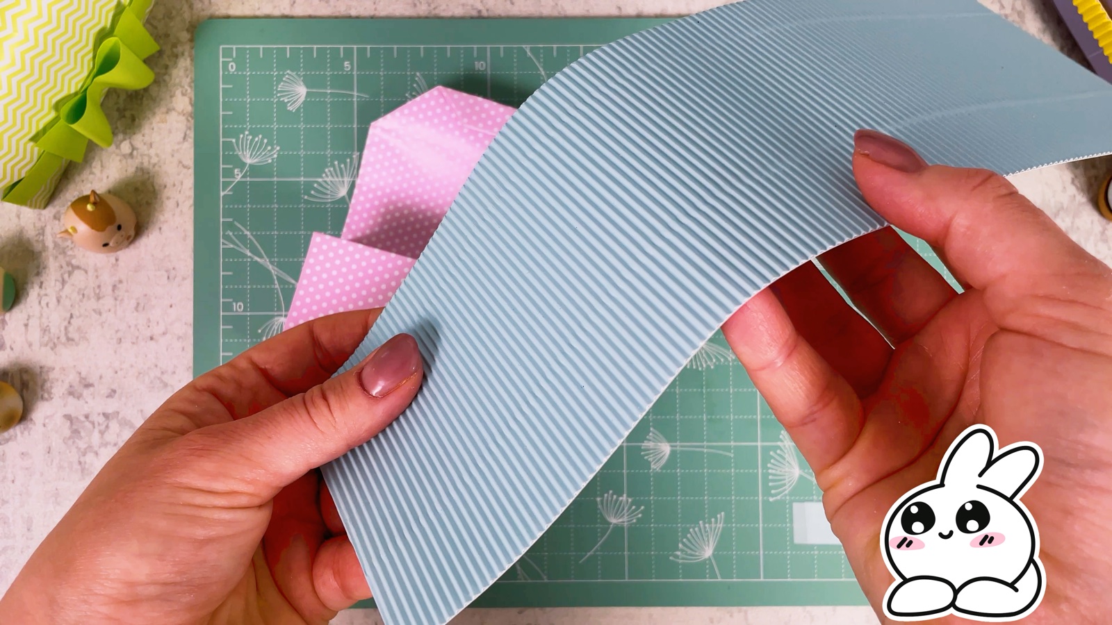 A sheet of light blue corrugated paper held next to the folded purse