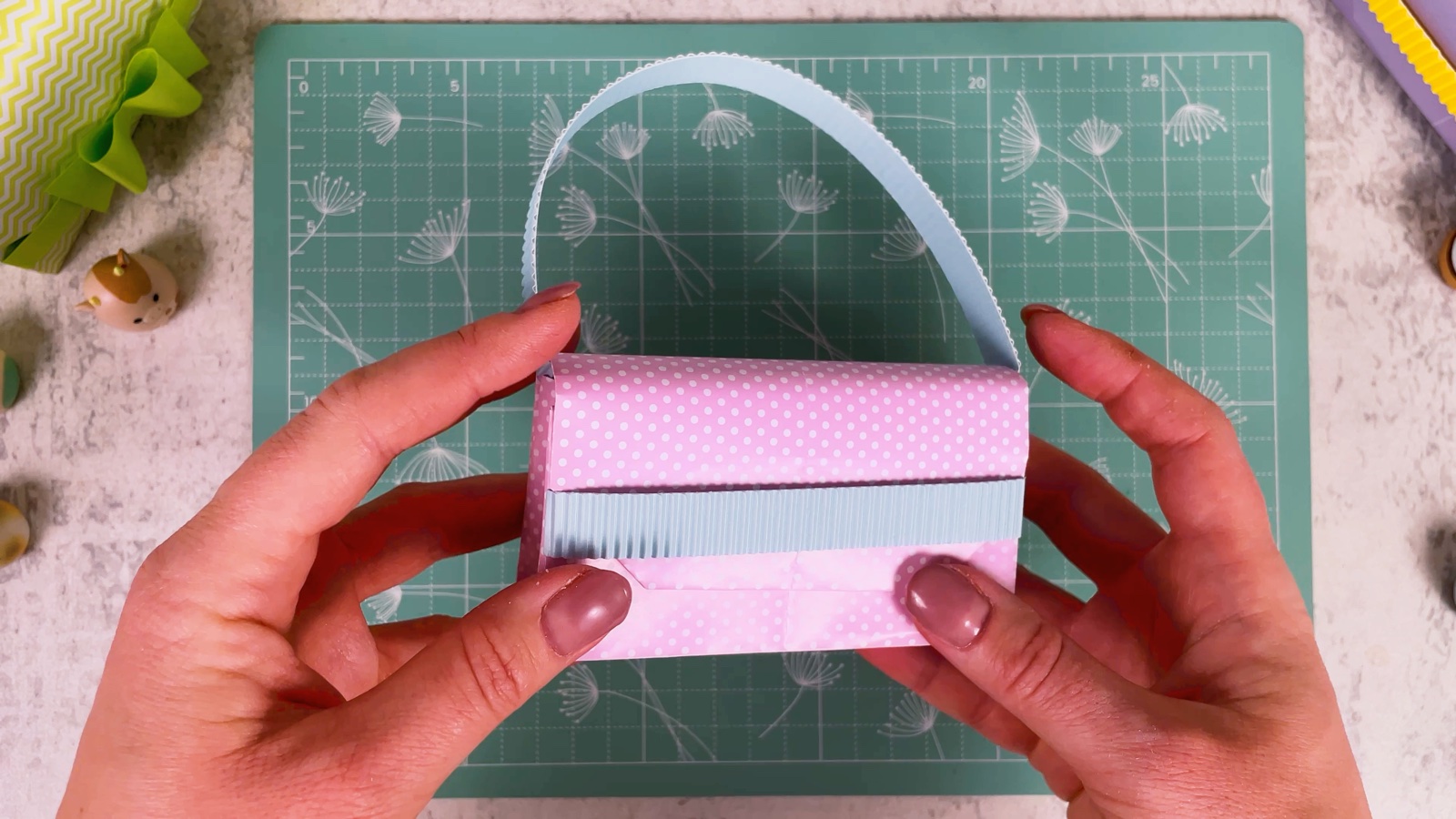 The purse with a blue corrugated band across the front and the handle on top