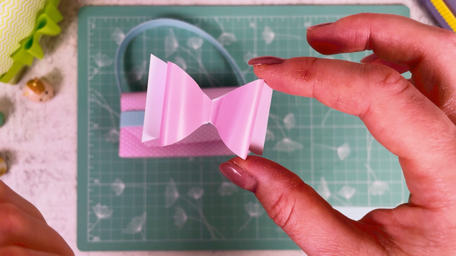 A finished pink paper bow held up in front of the purse