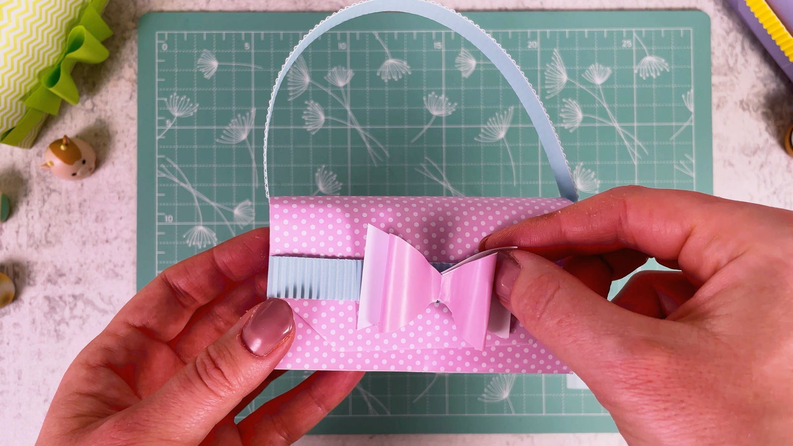 Pressing the pink bow onto the blue band at the front of the purse