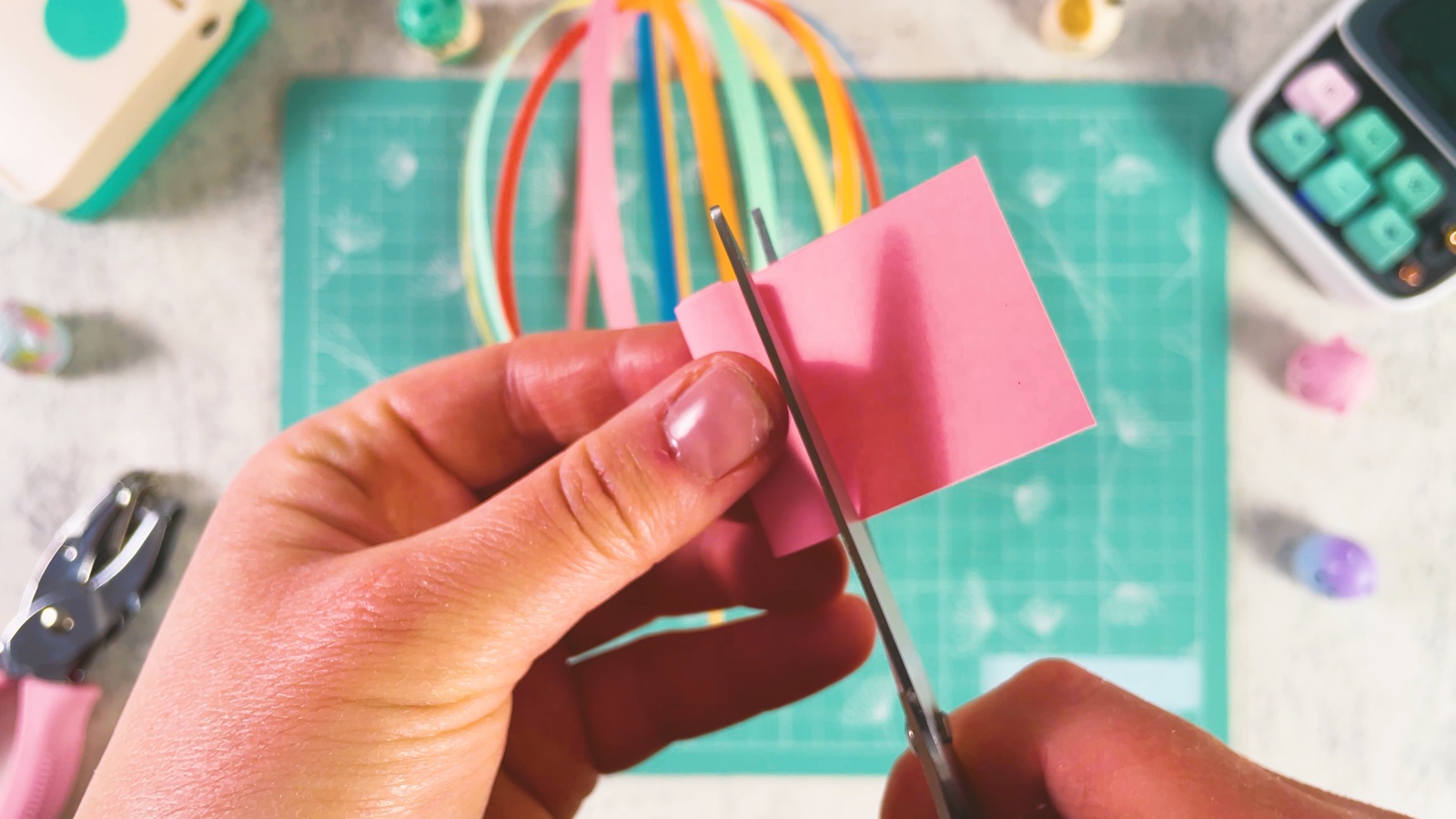 Se recorta un pedacito de papel rosa con tijeras