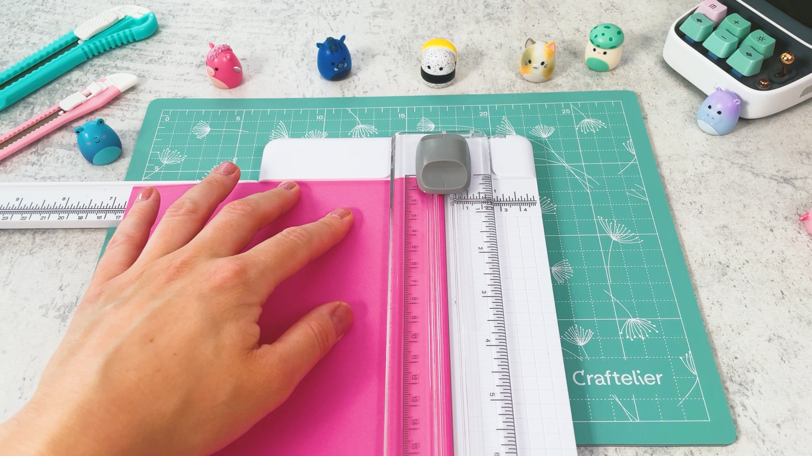 Trimming a sheet of pink paper into a square with a paper trimmer
