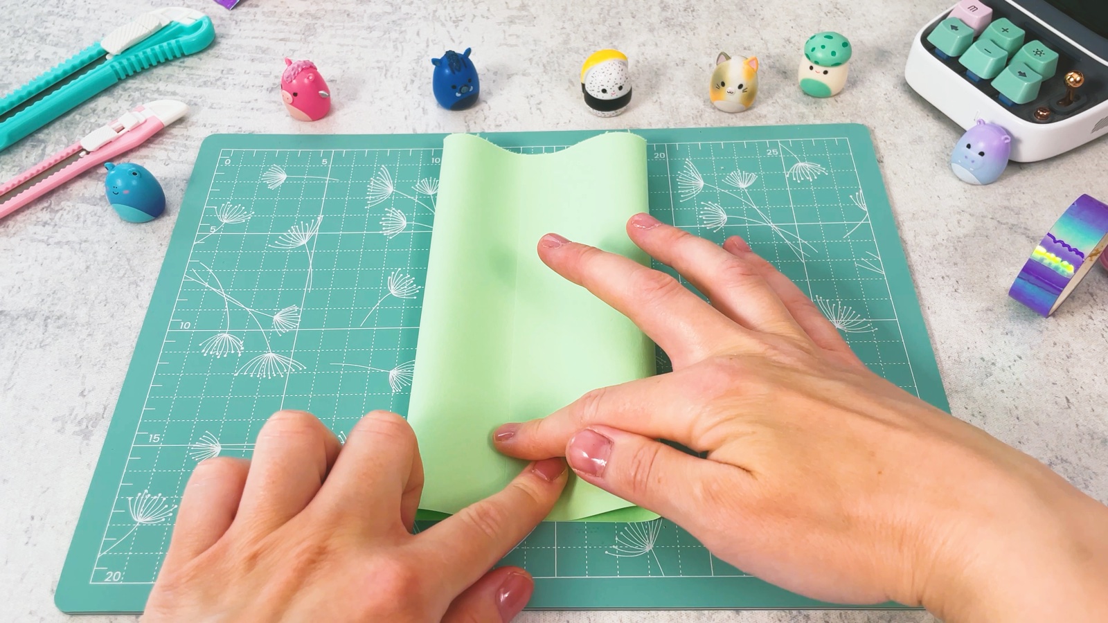 Pressing the second side over the first to make a flat green paper tube