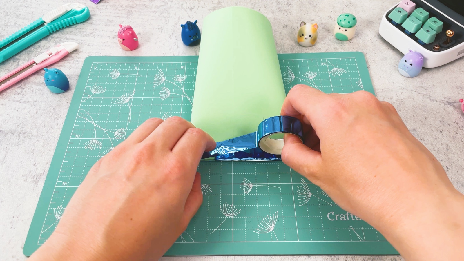 Sticking blue shiny tape along the bottom edge of the green bag