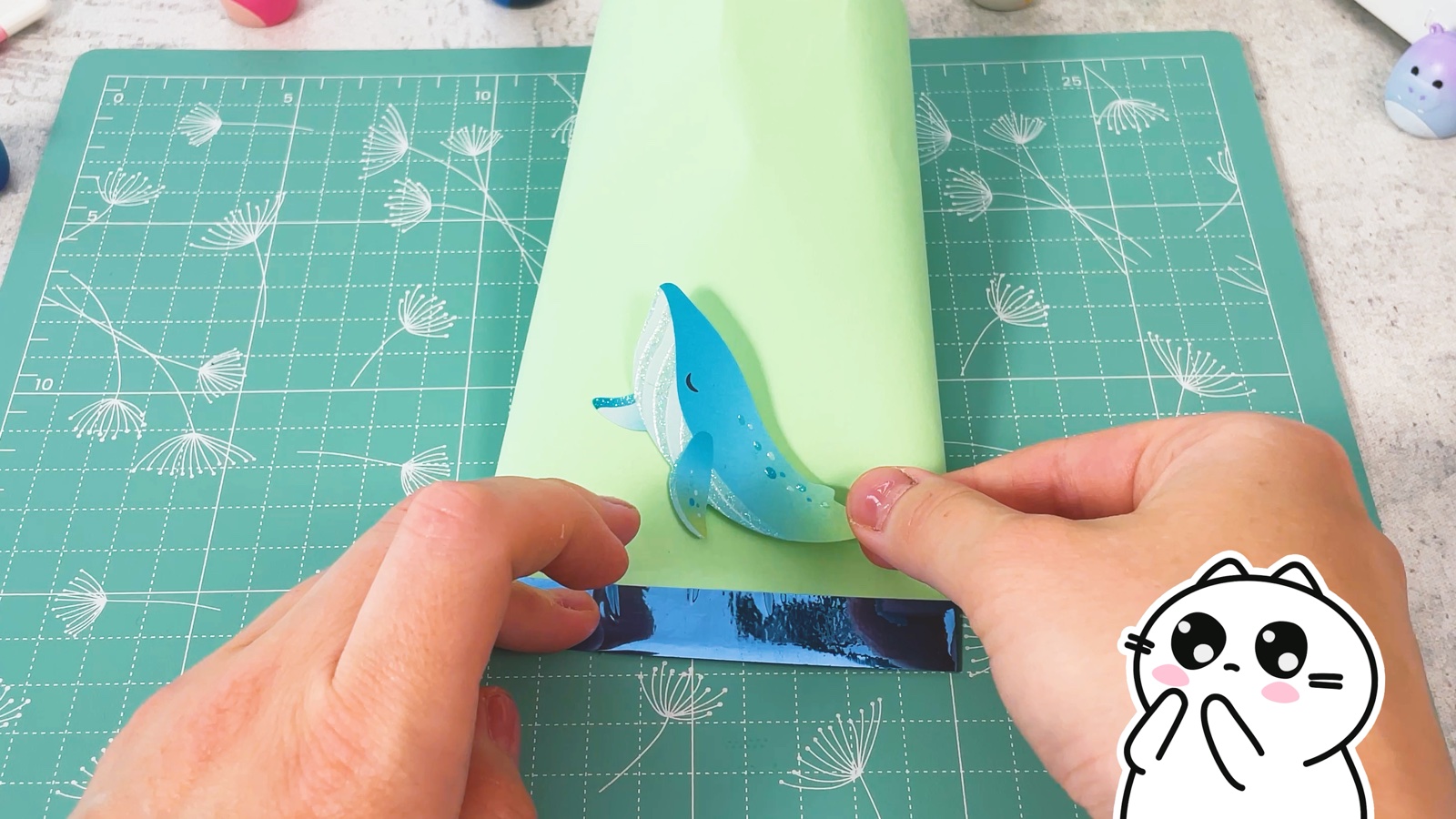 Pressing a blue whale sticker onto the front of the green bag