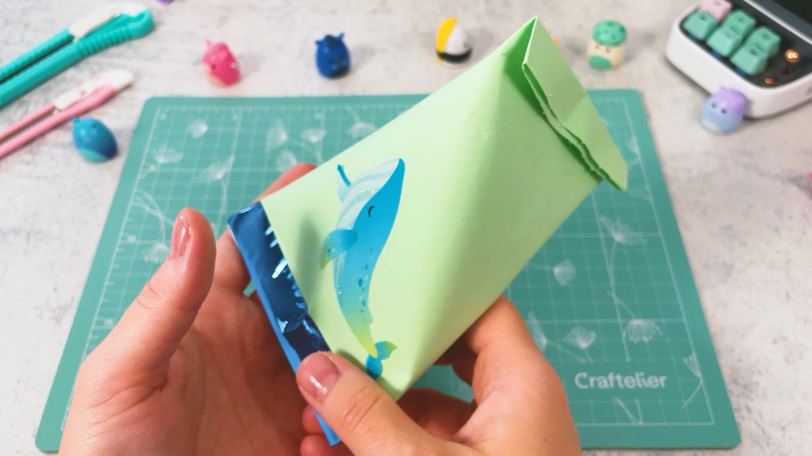 The finished green bag with a whale sticker, held up to show its pyramid shape