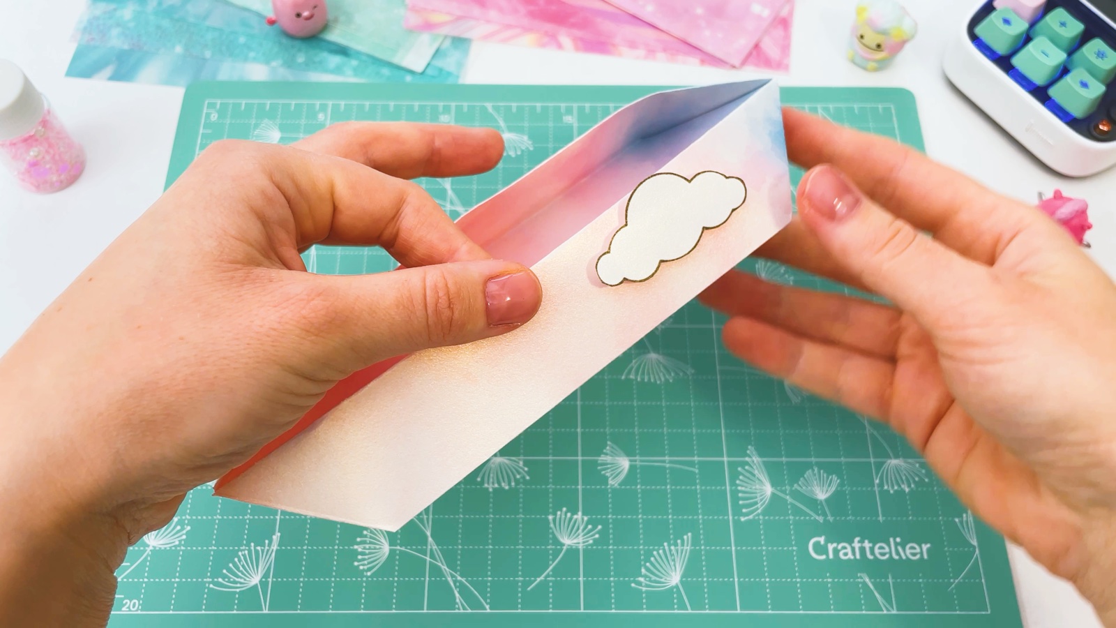 Pressing a white cloud sticker onto the side of the paper pencil case